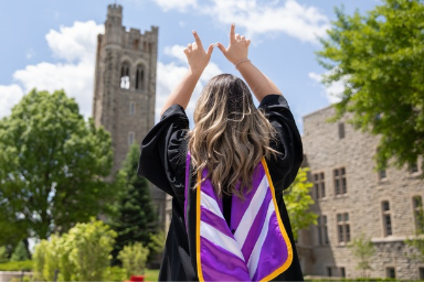 Graduate holding her hands up in a W formation in front of University College